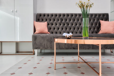 Grey sofa with pastel pink cushions daffodils in a vase glass coffee table