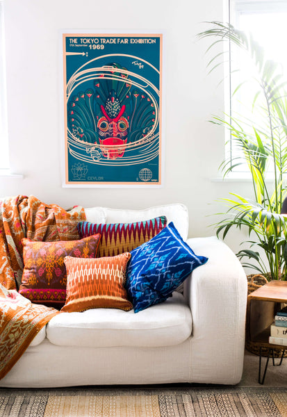 Four Patterned and Colourful Ikat Cushions from Bali on a White Sofa with Patterned Throw and a Poster of The Tokyo Trade Fair Exhibition