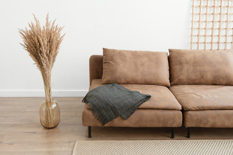 brown leather sofa with dried grasses in vase