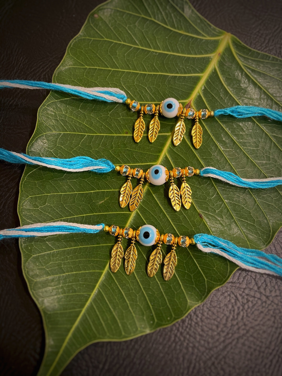 image for (Combo of 3) Fancy Round Evil Eye Rakhi Designs Leaf Pendant Beads & Blue/White Mauli Raksha Bandhan