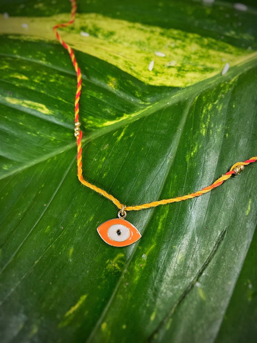 image for Fancy Orange Evil Eye Charm Designer Rakhi With Multicolored Thread For Raksha Bandhan Celebration