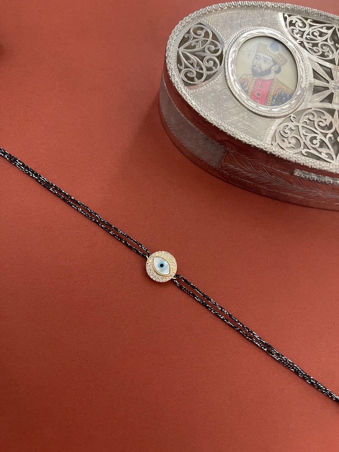 image for Designer Diamond Rakhi Round Evil Eye Charm With Black Thread Rakhi For Raksha Bandhan