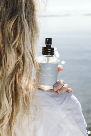 Nourishing sea salt spray next to blonde hair at beach 