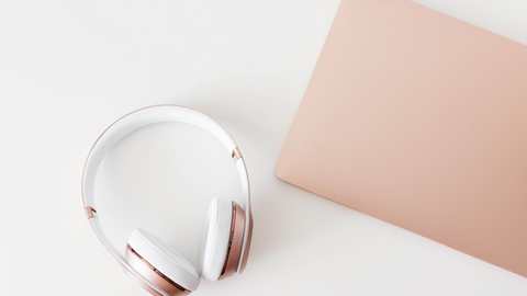 white headphones with a light pink edge around the earcuffs. Pink laptop.