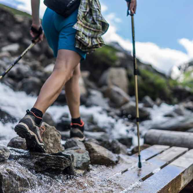 hiker with trekking poles on bridge