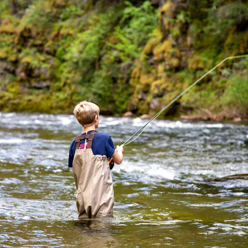 boy fly fishing on river