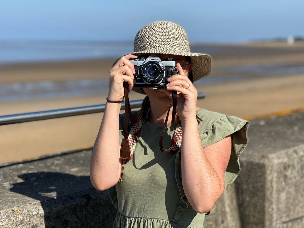 How to Shoot Film on a Budget| Lady holding a film camera to take a photo