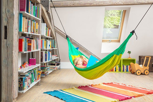 children reading a book together in a hammock