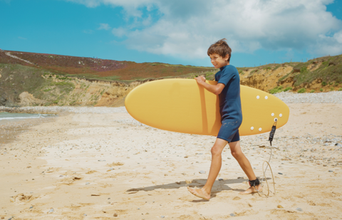 Young surfer with kids foam surfboard.