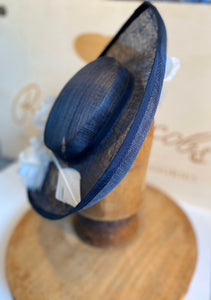 Navy blue pervher mother of the bride hat, with white flowers and arrow feathers. Rivka jacobs millinery. hats Uk
