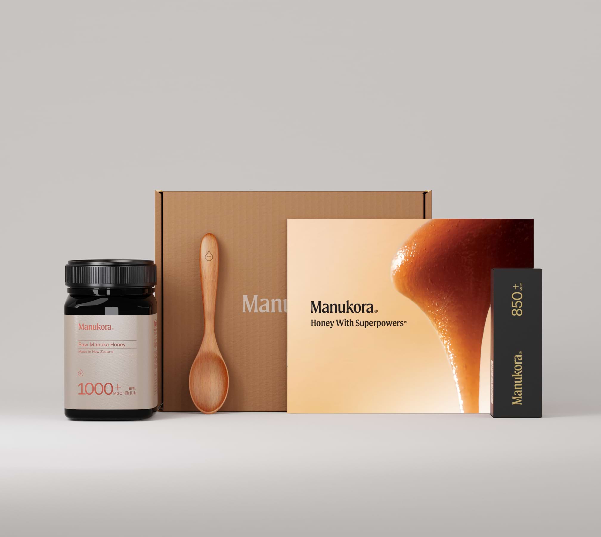 Manukora Manuka honey product set, including jar, wooden spoon, and packaging box.