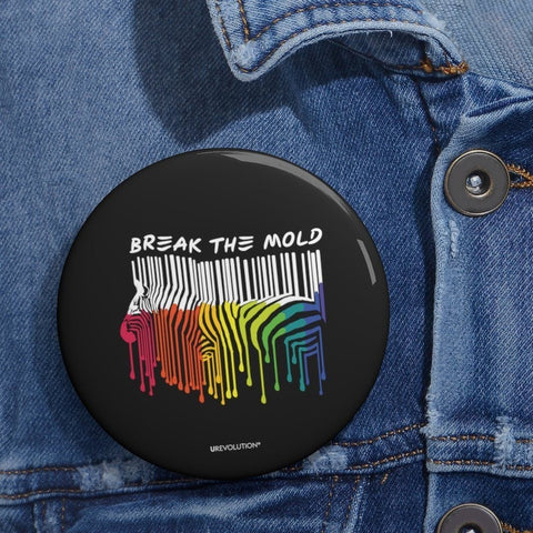 An image of a black round break the mold pin. In the middle of the pin is a graphic of zebra in the silhouette of a barcode. The top half of the zebra are vertical white stripes, which then change just below the back into the colors of the rainbow. The bottom of each stripe has a paint drip mark. Just above the zebra's back is the phrase, in upper case, 'break the mold.' At the bottom of the pin is the brand name in the upper case, URevolution® The pin is pinned to a blue denim jacket.