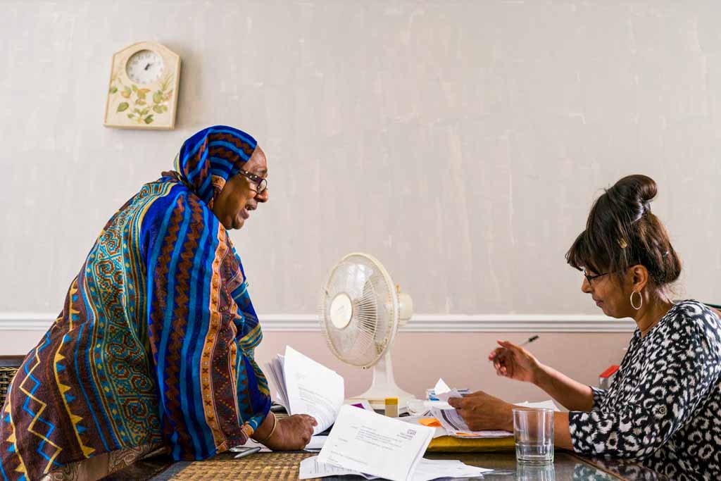 Photograph of Sarifa Patel with her personal assistant working at a table in her living room