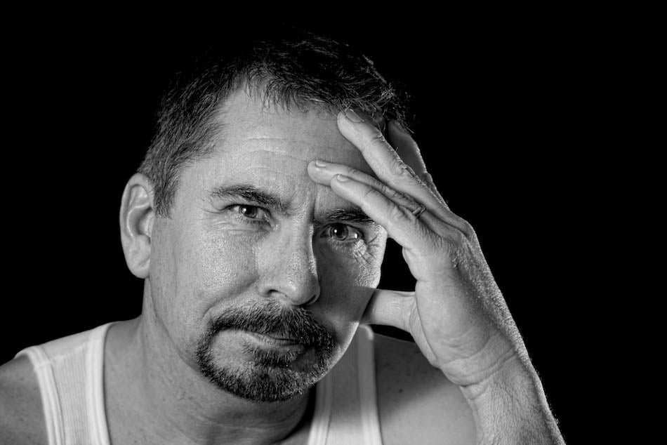 A black and white latino man stars intently at the camera. Image for an article on racism and depression.