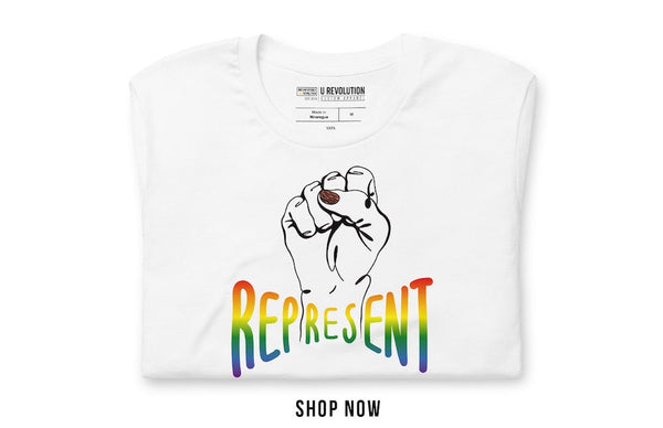 Photo of a white-color Represent Pride Tee. In the middle of the represent pride tee is a black line drawing of a raised clenched fist, with the handwritten word "represent," written in blended upper case rainbow pride colors: red, orange, yellow, green, indigo, and violet.