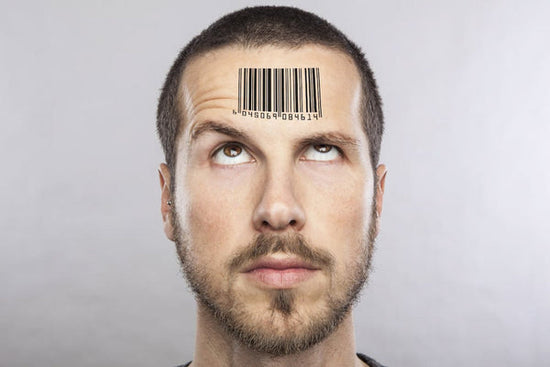 Head and neck portrait of a young man with a bar code printed on is forehead. His eyes are turned upward as he is trying to see what's on his forehead as he tries to figure out if he should say autistic person or person with autism.