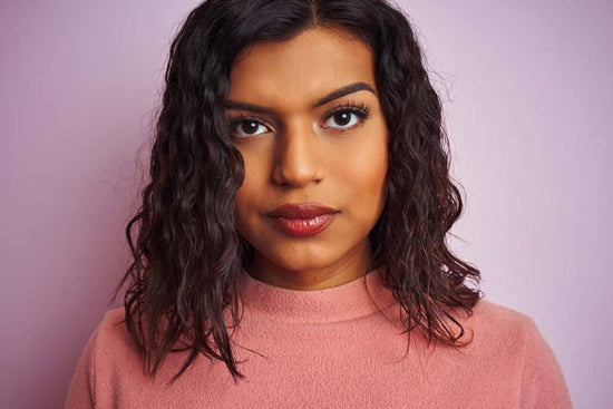 Recovering from an eating disorder: a photo of a young transgender woman standing over an isolated pink background with a confident expression on their face.