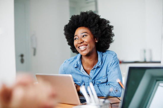 A photo of smiling employee at their desk happy about disclosing mental illness at work.