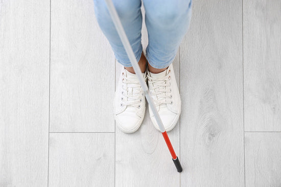 Photo for article on why employer perceptions about blind people are wrong. Top view of Blind person with long cane standing indoors.