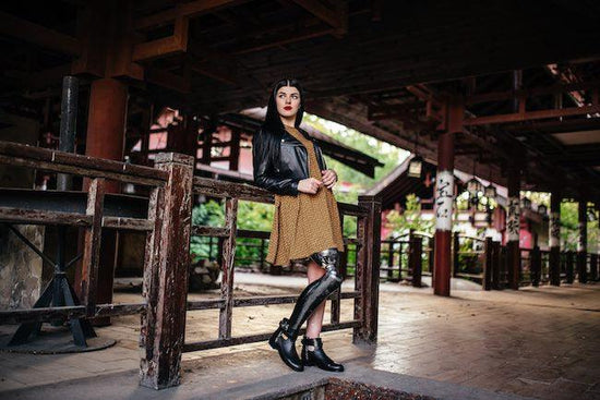 Models with disabilities: a stunning woman poses in what looks like an old building of Chinese history, but there aren't many inside details, so we can't be sure. She is wearing a mustard dress with a chic black leather jacket over it.