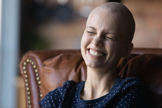 Close up of happy young sick woman with cancer laughing while reading funny personal cancer blogs.