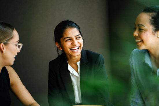 How to balance mental health struggles with your career: a photo of a three diverse women laughing at work