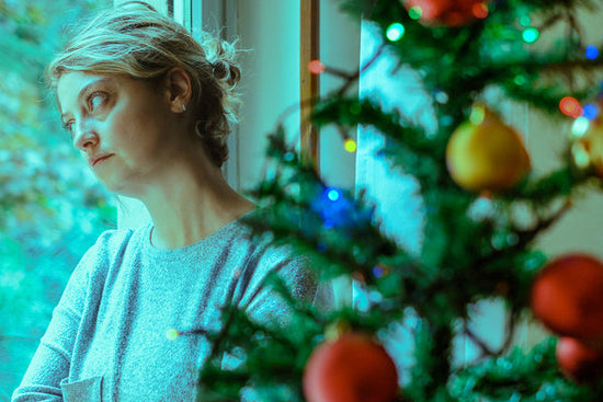 How to deal with seasonal depression: a woman leaning against a window looks sad/