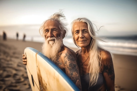 Vivir para ti mismo: una IA genera una foto de una pareja mayor con tatuajes de pie en una playa con una tabla de surf. 