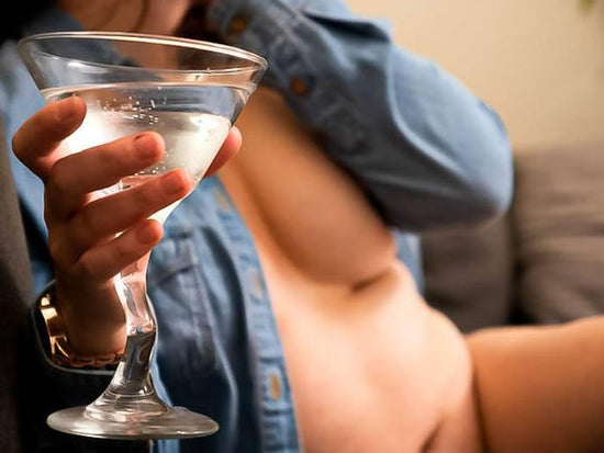 Tasteful photo of author in nothing but a faded blue denim shirt holding a martini glass. Image for artilce about being a disabled sex worker with a chronic illness, and working as a disabled escort for the disabled.