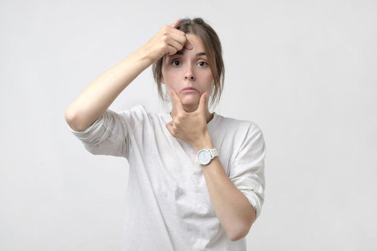 Living with kyphosis is a cause of chronic pain. This is a photo of a woman in a white long-sleeved t-shirt pulling a smile on her face. The picture conveys the concept of loss of work or being alone in pain.