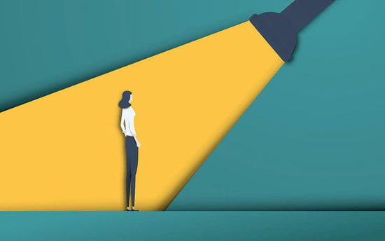 A paper collage of a person standing in the middle of a bright yellow spotlight, which is an analogy for what it is like living with Tourette Syndrome