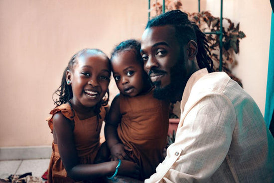 Photo for a story, 'my bipolar sister.' A beautiful warm photo of an African-American dad and his two young daughters posing together for a portrait. The dad is smiling and the older daughter is laughing.