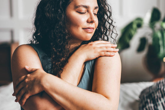 A young woman in a grey top touches her skin as a prelude to sex with ulcerative colitis