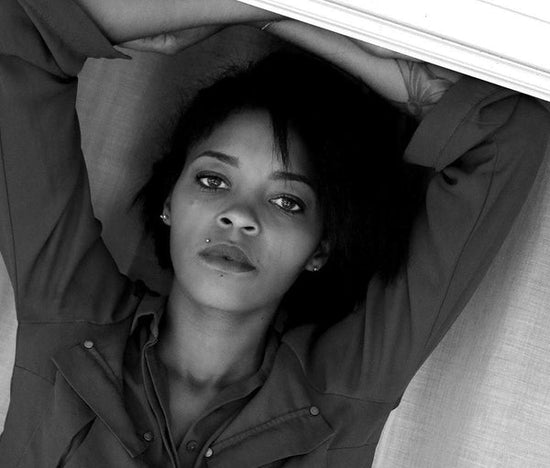 Toxic positivity: a black and white of a person lying down on their back with they arms folded on top of their head. The person is looking directly at the camera.