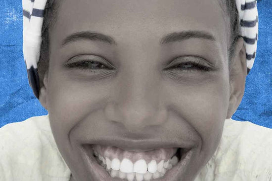 Very closeup portrait of person whose hair is covered and has a bright smile. 