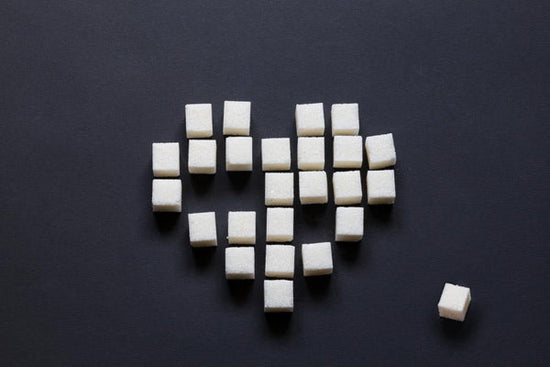 Dating someone with type 1 diabetes: photo of a heart on black background made up of individual white sugar cubes. Three of the cubes are missing from the heart shape. One cube is scattered off to the side. Image for an article on: 