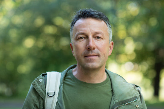 Depression is like quicksand: a photo of a middle aged man wearing a green jacket in a park. He is looking directly at the camera.