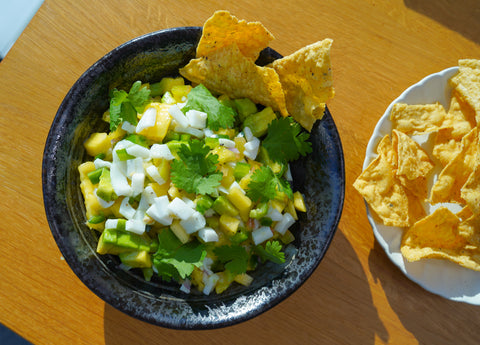 Coconut salsa served with corn nacho chips, coriander and lime