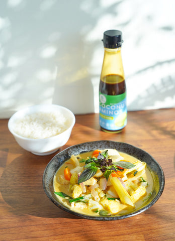 Vegan coconut green curry made with copra's coconut aminos and served with a bowl of jasmine rice