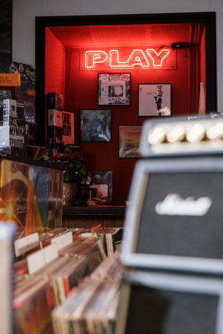 Record shop with the best vinyl records of 2020, framed albums, and a neon signed reading “play”
