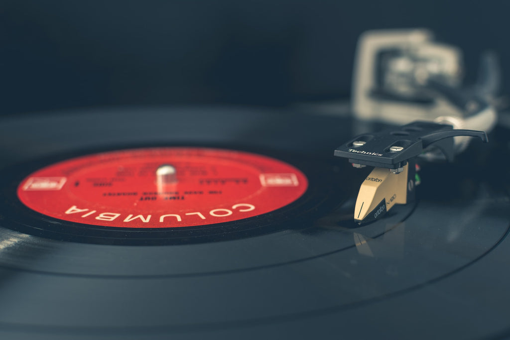 a close-up photo of a black record with a reed label on a record player with the needle on the record