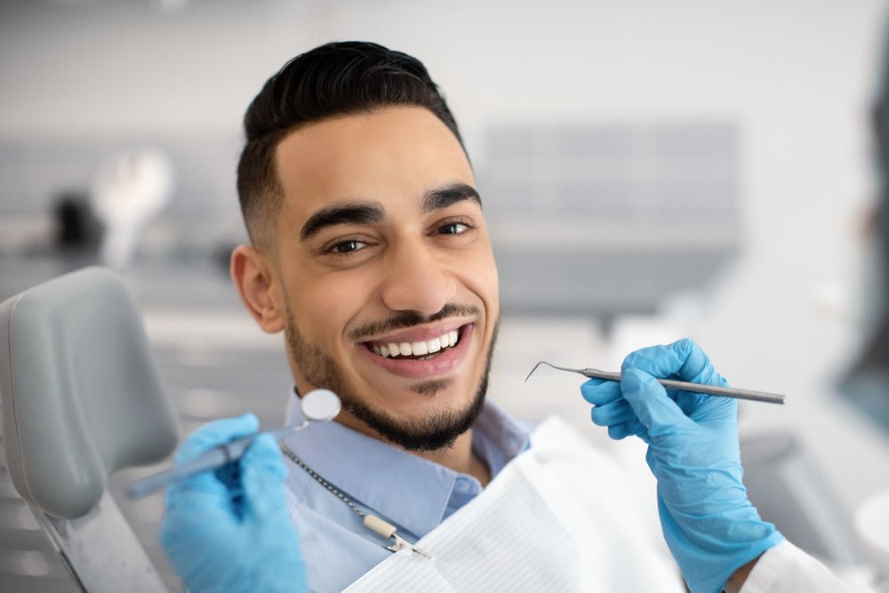 Portrait Of Happy Man Sitting At Dentist Chair In Modern Clinic