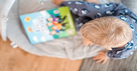 A photo of a toddler looking at a book.