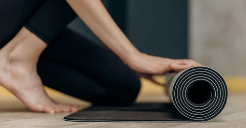 A person rolling a yoga mat. 