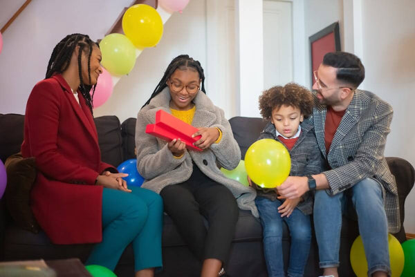 A family on a couch celebrating their child moving out with a gift