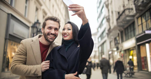 A couple taking a selfie like tourists, which you can be to make Valentine’s Day extra special, even if that means exploring your hometown. 