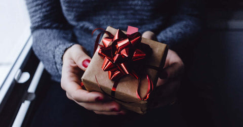 A person holding a wrapped present as an example of gifts for friends and loved ones moving away