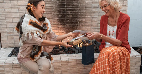 An Asian woman exchanging gifts with an older Caucasian woman.