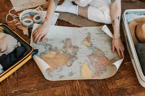 A person packing for a trip and opening a world map