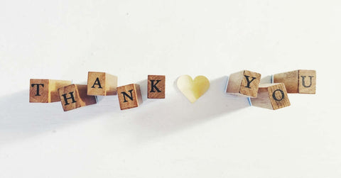 Wooden blocks spelling “thank you” on a white surface